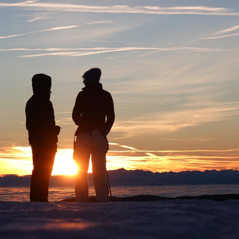 Zwei Personen im Sonnenaufgang Gegenlicht